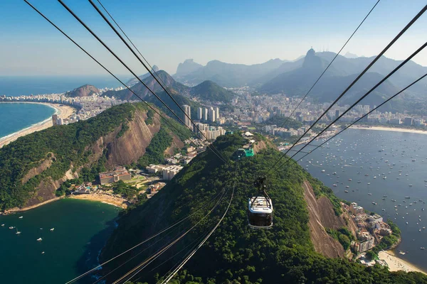美しい景色を望むシュガーローフ山またはリオデジャネイロ市の後ろに近づくケーブルカー — ストック写真