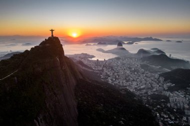 Rio de Janeiro, Brezilya - 10 Haziran 2023: Kurtarıcı İsa Corcovado Dağı 'nın tepesinde gün doğumunda ufuk çizgisinde Şekerleme Dağı ile birlikte.