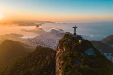 Rio de Janeiro, Brezilya - 10 Haziran 2023: Kurtarıcı İsa Corcovado Dağı 'nın tepesinde gün doğumunda ufuk çizgisinde Şekerleme Dağı ile birlikte.