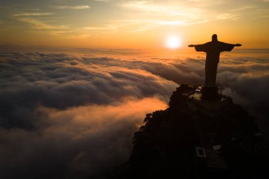 Rio de Janeiro, Brezilya - 11 Nisan 2024: Güneş doğarken Corcovado dağının tepesindeki Kurtarıcı İsa heykelinin dramatik manzarası.