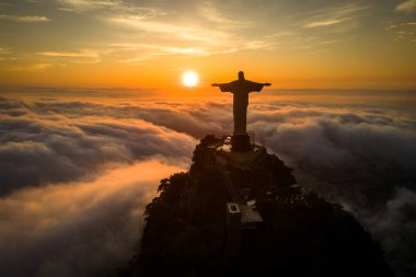 Rio de Janeiro, Brezilya - 11 Nisan 2024: Güneş doğarken Corcovado dağının tepesindeki Kurtarıcı İsa heykelinin dramatik manzarası.