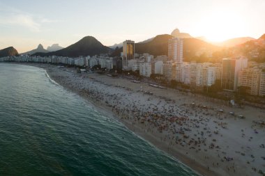 Kalabalık Copacabana Sahili ve Günbatımındaki Dağlar, Rio de Janeiro, Brezilya