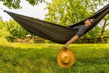 Bereketli yeşil bir ortamda, bir hamakta hasır şapkayla uzanan sükuneti hissedin..