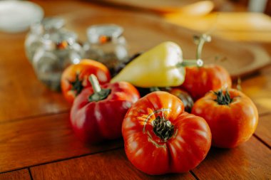 Domates ve biber, sade ahşap bir yüzeyde doğal ışıkta dizilmiş..