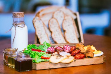 Ekmek, süt, sosis, marul ve mantar da dahil olmak üzere çeşitli kahvaltı yemekleri.