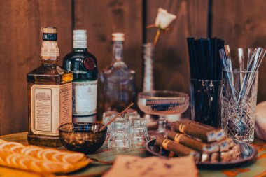 Sergilenen viski şişeleri, purolar ve zarif cam eşyalar ile sofistike bir düzen.