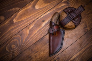 Sanatsal bıçak, matara ve deri teçhizat parlatmalı ahşap tahtalara dizilmiş..