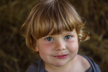 Kahverengi saçlı, iri gözlü, mutlu bir çocuğun sevimli yakın çekimi..