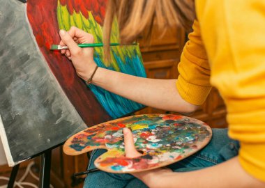 Bir paletle tuvale resim çizen kişi, canlı bir sanat şaheseri yaratıyor..