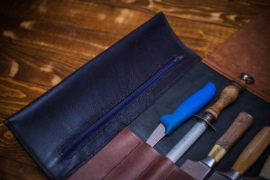 Ahşap bir yüzeyde deri kapaklı profesyonel bıçak seti..