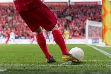 Futbolcu köşeyi dönüyor. Futbol maçında oyuncunun bacakları ve topun ayrıntıları.