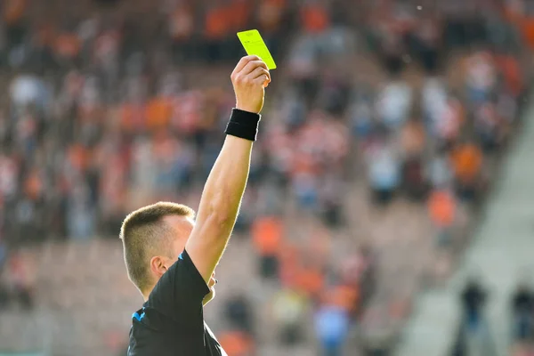 レフリーはスタジアムでサッカーの試合中に黄色のカードを示しています — ストック写真