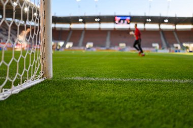 Net and the post in the football goal at the  stadium and goalkeeper in the background.