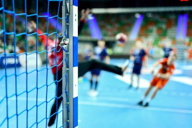 Hentbol kale direğinin ayrıntıları ve arka planda net ve penaltı atışı.