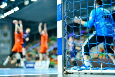 Hentbol kale direğinin ayrıntıları ve arka planda net ve penaltı atışı.