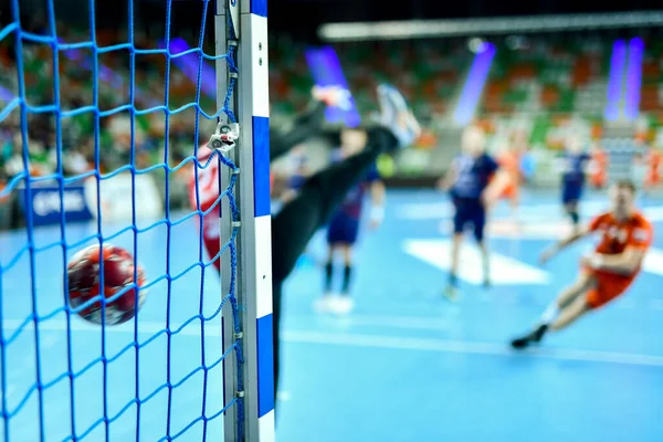 Hentbol kale direğinin ayrıntıları ve arka planda net ve penaltı atışı.