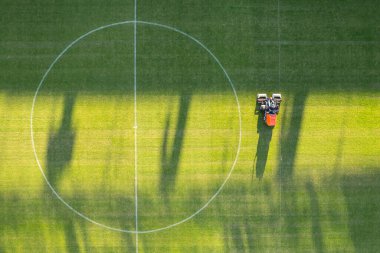 Futbol sahasında çim taşıyan adamın drone görüntüsü.