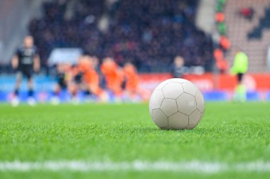 Futbol sahasındaki top ve stadyumdaki maçta arka plandaki oyuncular..