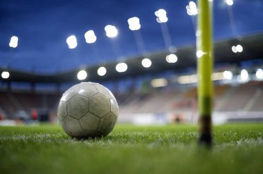 Stadyumdaki çimlerin üzerinde duran beyaz futbol topu.