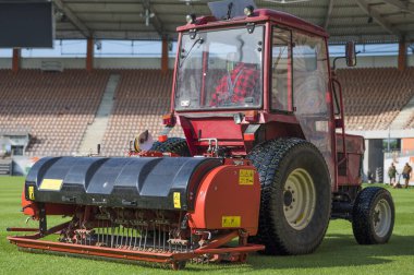 Man in tractor aerating a soccer field. clipart