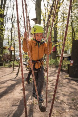 Küçük şirin bir çocuğun portresi Macera halat parkında ipte yürüyor