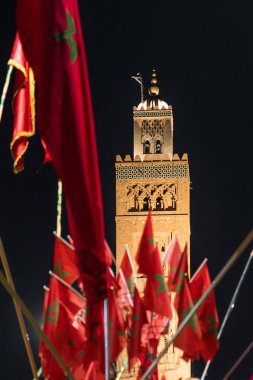 Geceleri ön planda Fas bayrakları olan bir Koutoubia camisi. 