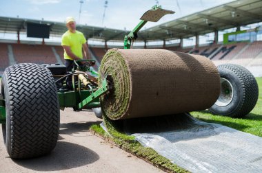 LUBIN, POLAND - 28 Mayıs 2021 Zaglebie Lubin Stadyumu 'ndaki bir futbol sahasında çimen döşeyen iki işçi