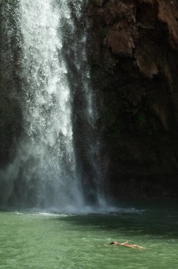 Fas 'ta güzel Ouzoud suları altında rahat bir kadın sırtüstü yüzüyor..