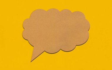 Sarı kağıtta kahverengi kağıt konuşma balonu. Reklam tasarımı için kopyalama alanı olan metin kutusu boş.