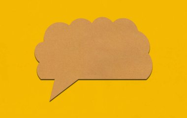 Sarı kağıtta kahverengi kağıt konuşma balonu. Reklam tasarımı için kopyalama alanı olan metin kutusu boş.