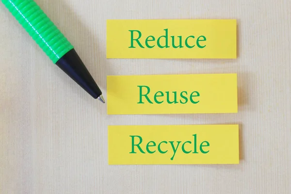 Green Pen pointing Text on yellow paper note with the words of Reduce, Reuse and Recycle for design in your work concept 3R in Reducing the amount of waste.