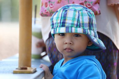 Mavi gömlekli çocuğun yüzüne odaklan ve yeşil bir şapka tak. Şaşırmış ve kameraya bakıyor..