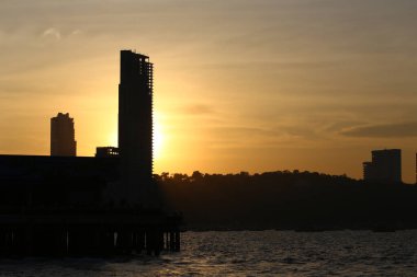 Akşam güneşinin batmak üzere olduğu yüksek binaların ve dağların silueti, Siluet tarzında Pattaya şehrinin görüntüsü.