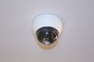 Toplantı odasının tavanına yerleştirilmiş kubbe şeklinde bir kamera, siyah lensli beyaz kamera..