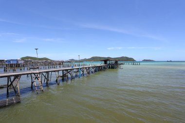 A wooden bridge leads into the sea at a resort on a clear day at Samae San Bay in Chonburi Province in Thailand, which is ideal for a vacation. clipart