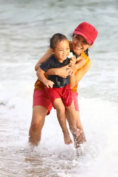 stock image Mother holding her child and playing on beach, Mother and child having fun to playing, Tropical sea beach of Thailand on a family vacation.