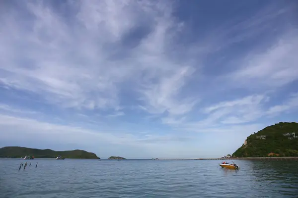 stock image The sea has floating ships and mountains surrounding it on a clear day with white clouds.