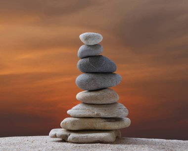 Günbatımında bir arkaplanda piramit şeklinde istiflenmiş taşlar ve çalışma, seyahat veya zen temasında tasarım için alanı kopyalamak.