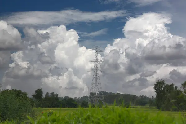 Stock image High-voltage electric towers between the cities stand in rice fields, with white clouds in the sky on a clear day, electrical poles do not yet have wires.