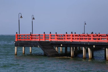 Denize doğru uzanan ve mavi gökyüzü manzaralı kırmızı köprü, Tayland 'ın Chonburi eyaletindeki deniz kenarı turistik yerleri..