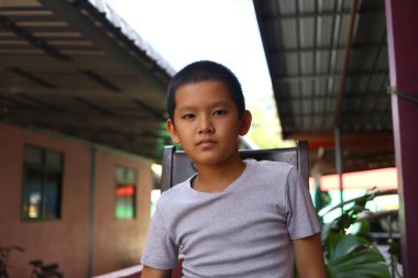 Açık havada oturan, sakin ve ciddi bir ifade sergileyen genç bir çocuğun portresi. Görüntü, genç bir ruhu doğal bir ortamda yakalıyor. Masumiyet ve çekicilik sergiliyor..