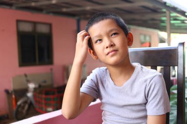 Düşünceli genç bir çocuk evde oturur, dalgın dalgın dalgın dalgın. Sıradan tavrı ve düşünceli ifadesi bir anlık yansıma ve masumiyeti yakalıyor..