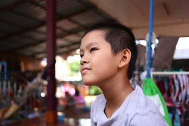 Düşünceli genç bir çocuk rahat bir evde oturur, sakin bir ifadeyle mesafeye bakar. Görüntü masumiyet ve neşeyi yakalar..