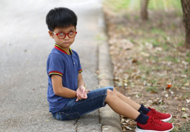 Gözlüklü genç bir çocuk düşünceli bir şekilde bir patikada oturur ve günlük tarzını sergiler. Dışarıdaki dingin ortam onun derin düşüncelere dalmasını sağlıyor..