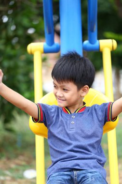 Neşeli bir çocuk, çocuk parkındaki renkli bir slaytta heyecanlı bir anın tadını çıkarıyor. Kaygısız çocukluk ve açık hava eğlencesinin özünü somutlaştırıyor..