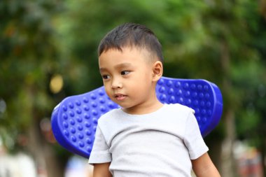 Neşeli bir çocuk dışarıda parkta oynamaktan zevk alır, masum bir mutluluk anını gösterir. Ayar açık hava aktiviteleri için mükemmel, güneşli bir günü yansıtıyor..