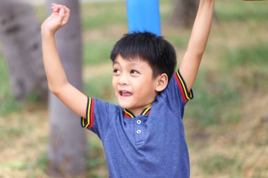 Neşeli bir çocuk enerjik bir parkta oyun zamanının tadını çıkarıyor. Sahne, çocukluğun özünü bir gülümseme ve güneşli gökyüzünün altında neşeli bir enerjiyle yakalar..