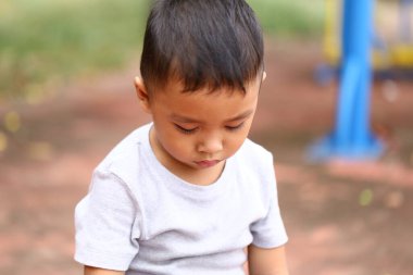 Düşünceli genç bir çocuk oyun alanında sessizce oturur ve hayatı düşünür. Huzurlu atmosfer çocukluğun masumiyetini canlı bir ortamda yakalar..