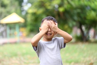 Neşeli bir çocuk güneşli bir parkta, neşeli bir mutluluk ve masumiyet ifadesi sergiliyor. Çocukluk anılarını yakalamak için mükemmel..
