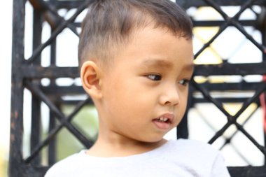 Düşünceli genç bir çocuğun dışarıda oturduğu görülüyor, sakin bir ifadeyle uzaklaşıyor. Bu görüntü çocukluğun masumiyetini ve merakını doğal ışıkta yakalar..